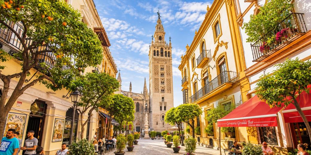 Via con aranci e tavolini all’aperto che sbocca sulla Giralda, accanto al quartiere di Santa Cruz
