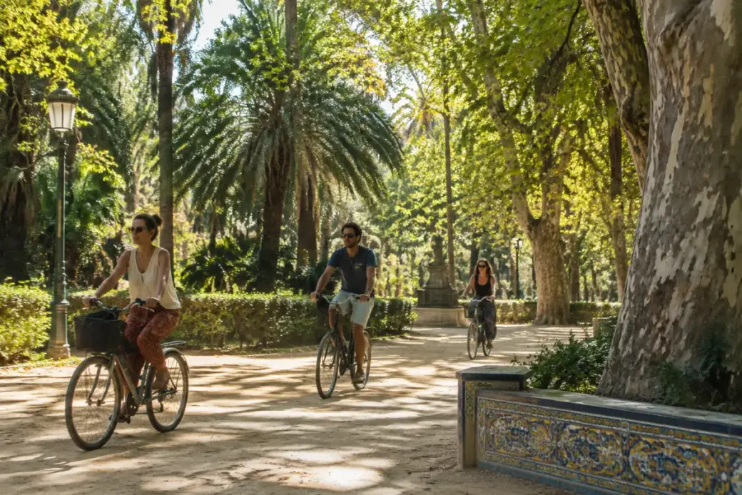 Ciclistas por un sendero de albero entre árboles en el parque de María Luisa