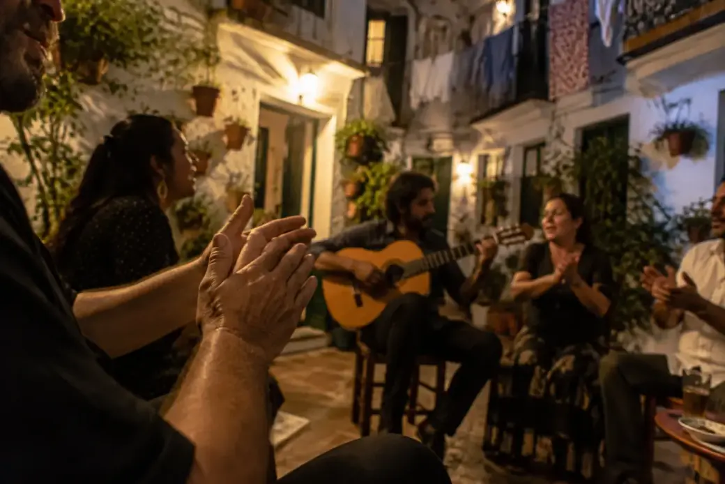 Palmas y guitarra flamenca entre vecinos en un corral de Triana de noche