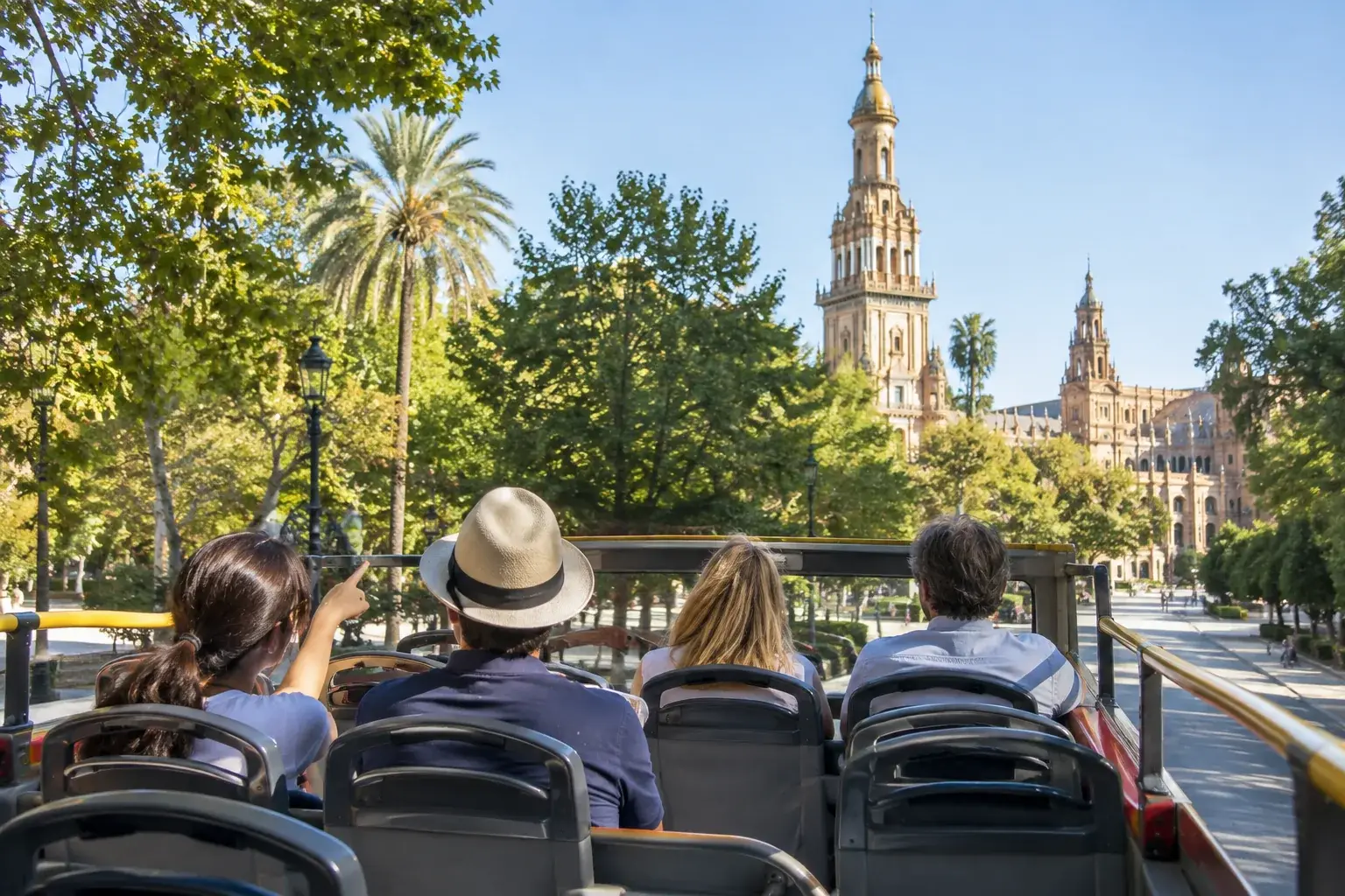 Pasajeros en la planta alta de un autobús panorámico pasando junto a las torres de la Plaza de España